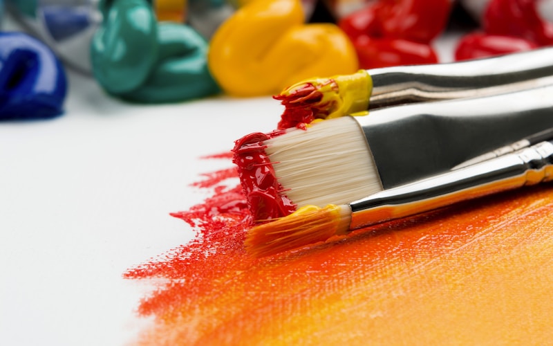 Pinceles con pintura de colores vivos sobre un lienzo durante el taller